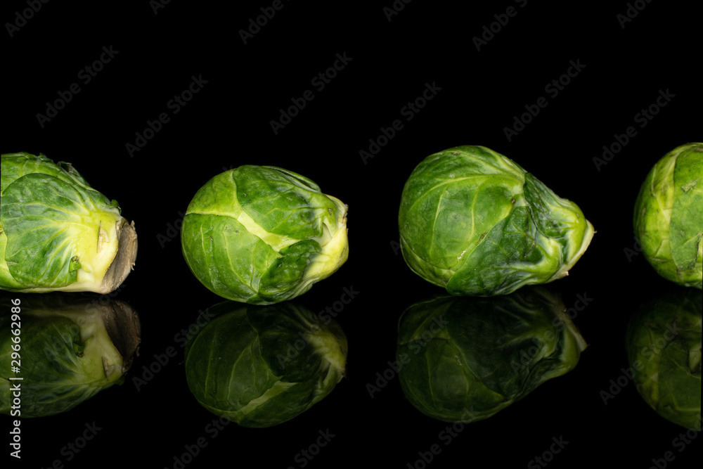 Group of four whole fresh green brussels sprout isolated on black glass Group of four whole fresh green brussels sprout isolated on black glass