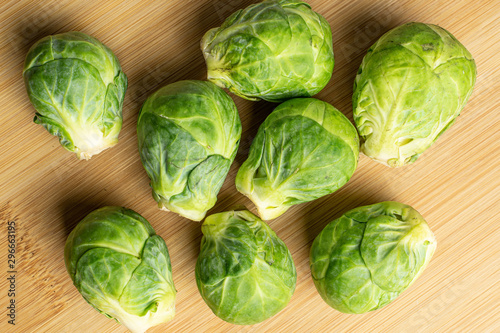 Group of eight whole fresh green brussels sprout flatlay on light wood
