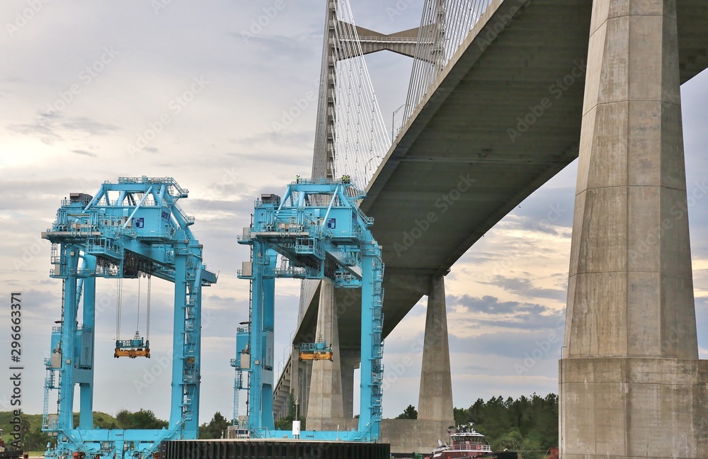 Fototapeta premium Port cargo cranes are transported on river under bridge using barge