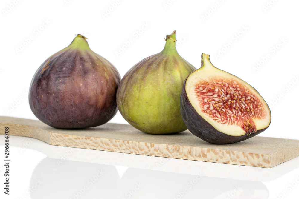 Group of two whole one half of sweet purple fig on wooden cutting board isolated on white background Group of two whole one half of sweet purple fig on wooden cutting board isolated on white background