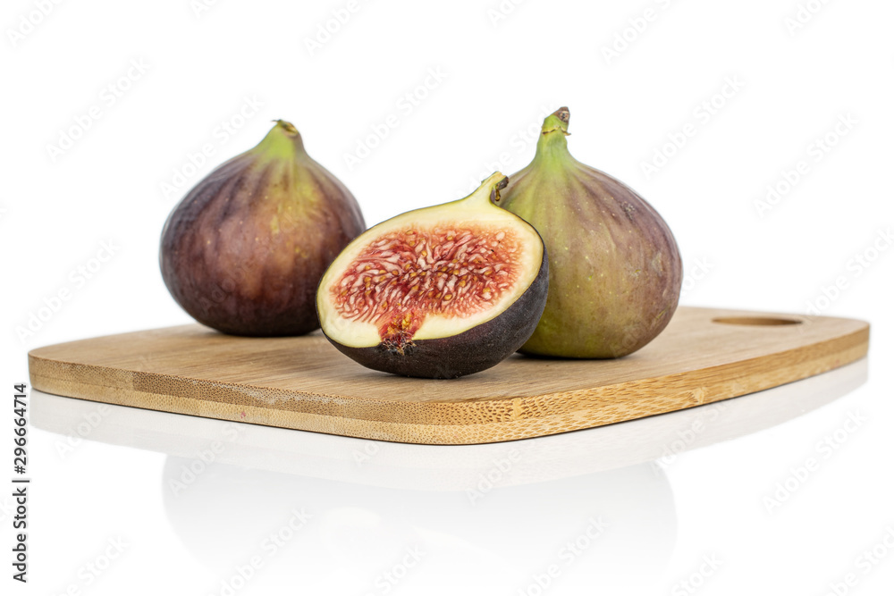 Group of two whole one half of sweet purple fig on bamboo cutting board isolated on white background Group of two whole one half of sweet purple fig on bamboo cutting board isolated on white background