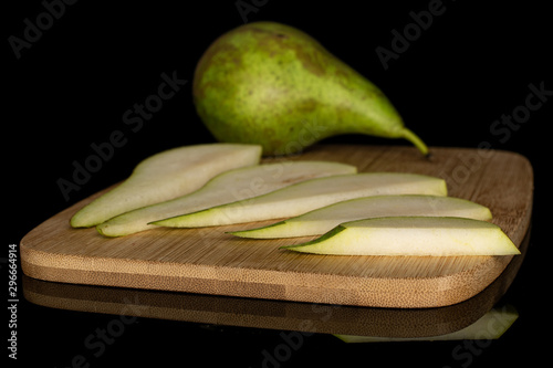 Group of one whole five slices of fresh green pear on bamboo cutting board isolated on black glass photo