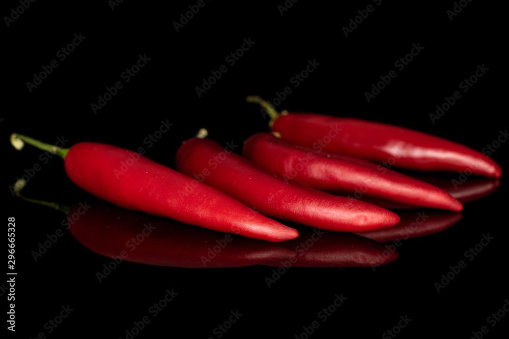 Group of four whole hot red chili cayenne isolated on black glass
