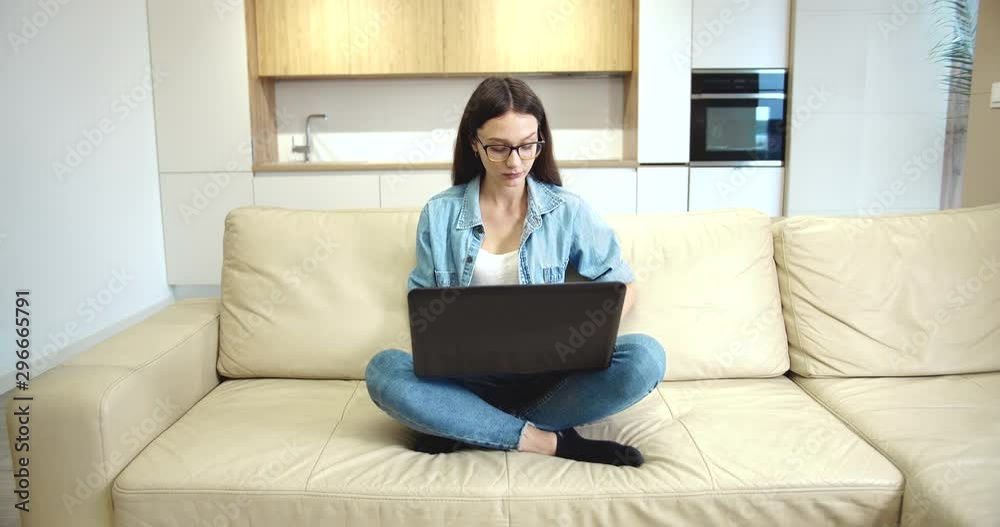 Satisfied female freelancer sitting in empty room and working on laptop, just moved in Satisfied female freelancer sitting in empty room and working on laptop, just moved in