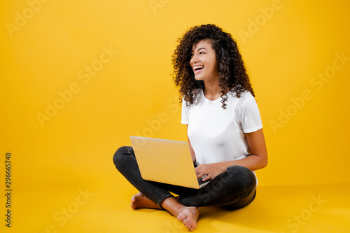 happy african black woman sitting with laptop isolated over yellow