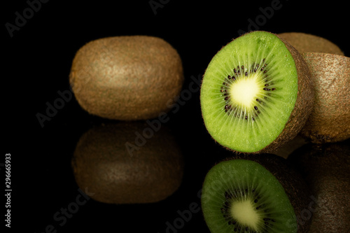 Group of two whole two halves of exotic brown kiwi isolated on black glass