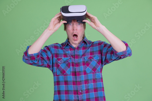 Young hipster man removing virtual reality headset while looking shocked