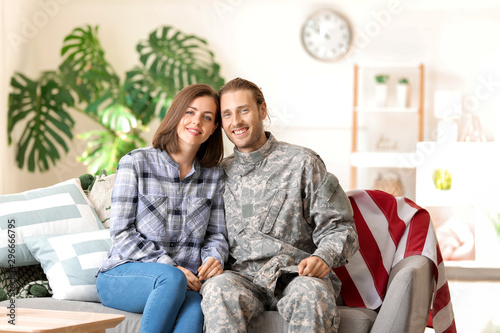 Canvastavla Happy military couple sitting on sofa at home, soldier and wife reunited, family
