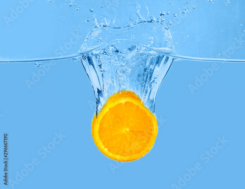 Fototapeta Naklejka Na Ścianę i Meble -  Falling of orange piece into water on light background