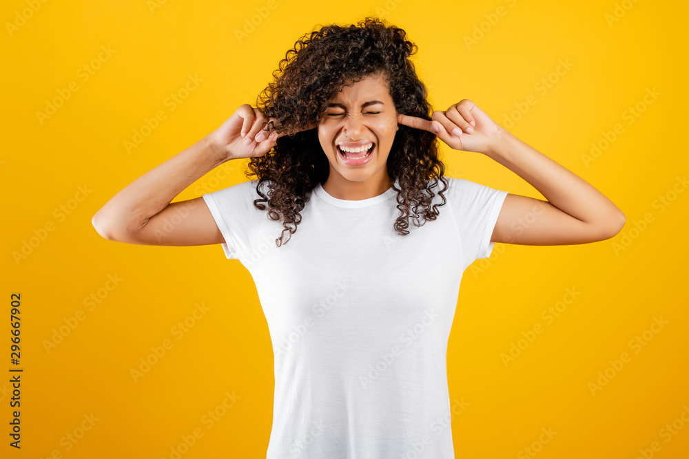 stressed black girl covering her ears isolated over yellow