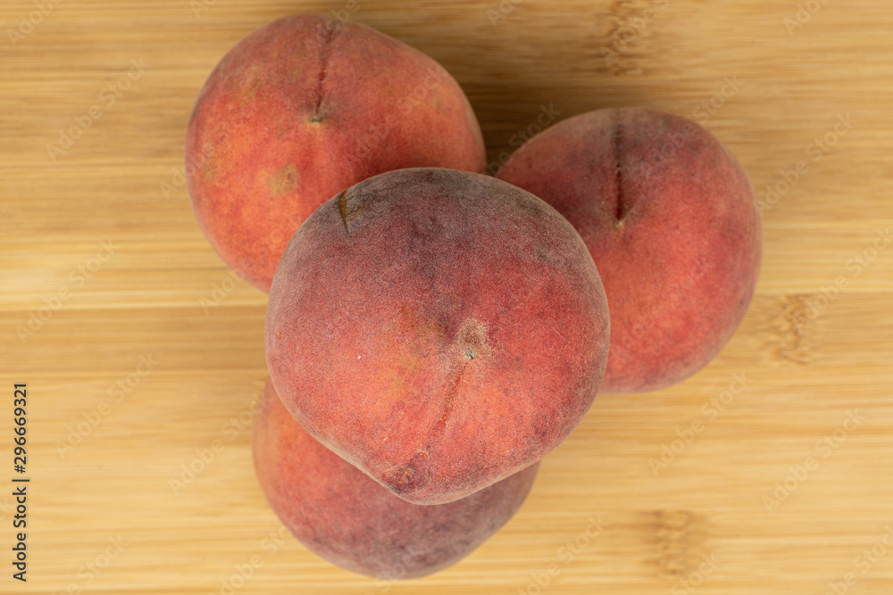 Group of four whole sweet red peach flatlay on light wood Group of four whole sweet red peach flatlay on light wood