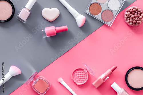 Decorative cosmetics frame on pink and grey background top view copy space