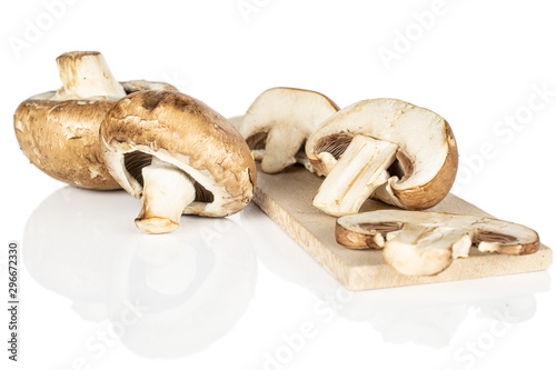 Group of two whole two halves one slice of fresh brown mushroom champignon on wooden cutting board isolated on white background