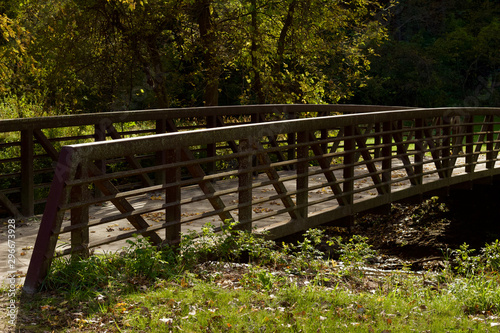 Landscape view of a rustic bridge over a river in a woodland natural public park area