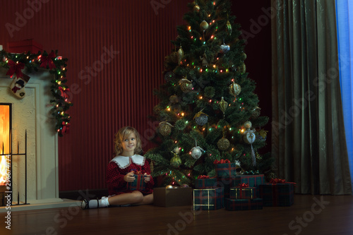 portrait of little girl is waiting for Santa coming in domestic environment