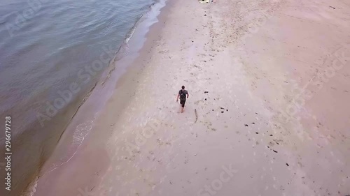 Aerial Shot of Man Walking On Sandy Beach on a Cloudy Day. Beach Walk Slowmotion. Man Walking on a Beach Slowmotion,