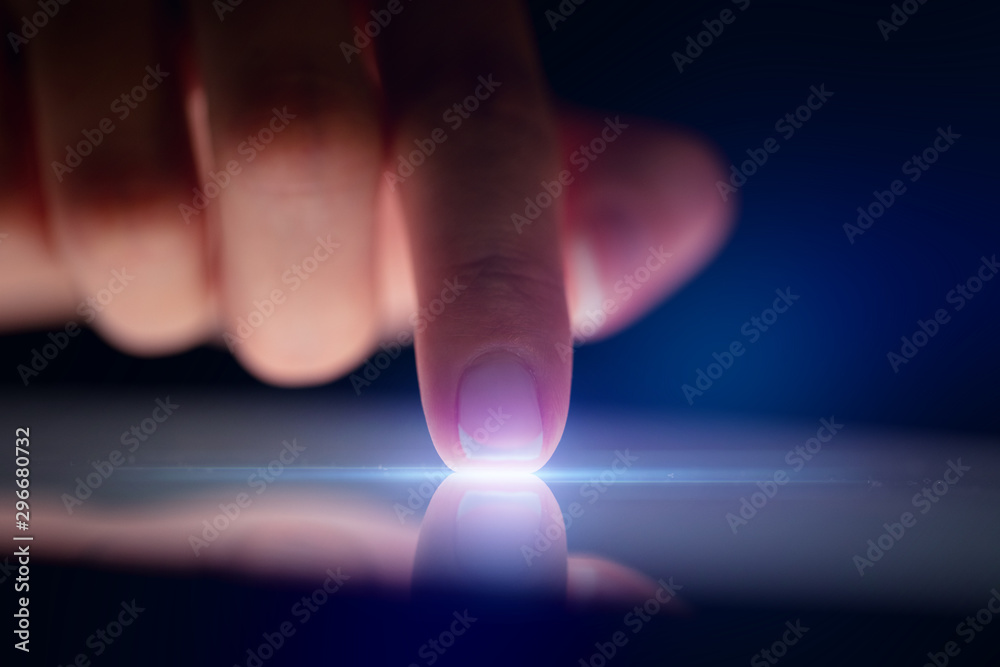 Finger touching tablet with dark background with copyspace - obrazy, fototapety, plakaty 