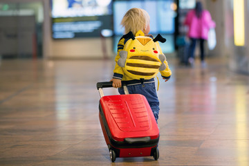 Cute  baby boy waiting boarding to flight in airport transit hall near departure gate. Active family lifestyle travel by air with child
