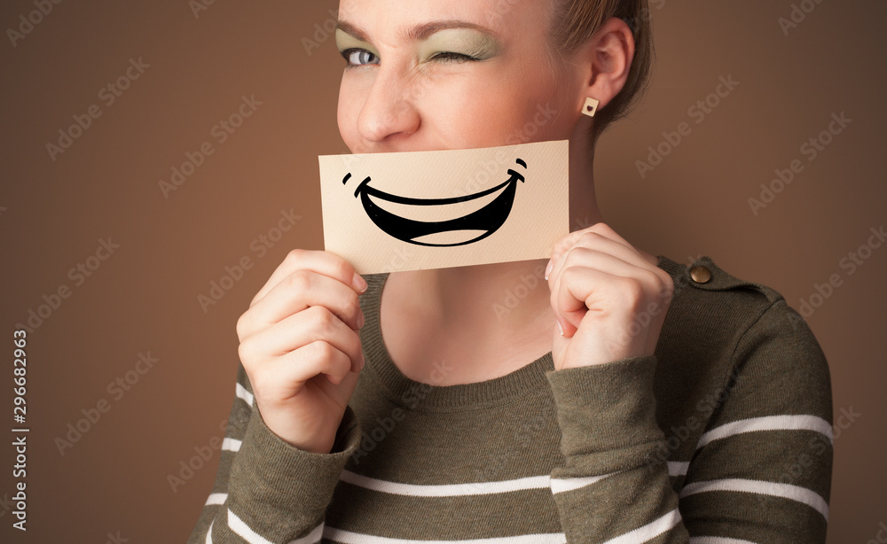Person holding card in front of his mouth with ironic smile Person holding card in front of his mouth with ironic smile