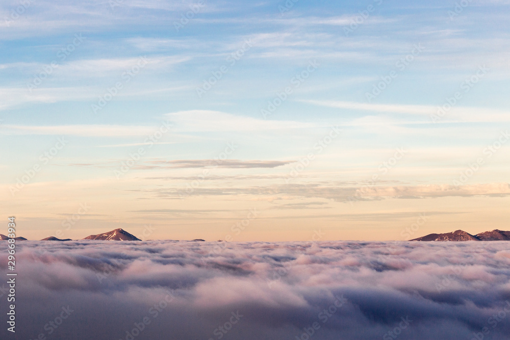 Distant mountains above a sea of fog like islands at sunset