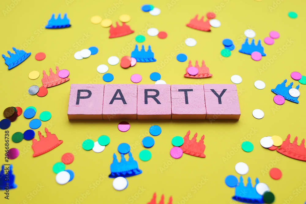 Party word with colorful confetti, on yellow background. Holiday concept.