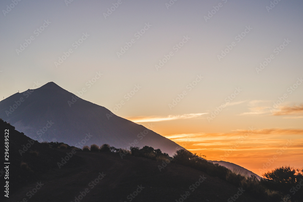 Sunset or sunrise beautiful landscape moment at the mountain - high peak vulcan and coloured sunlight in background - plants and desertic vegetation - beauty of outdoor nature