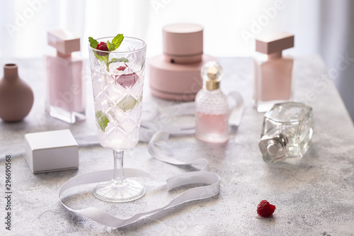 Pink fresh cocktail with raspberry and mint on table with rose bottle perfume bottle. Concept for female drink.