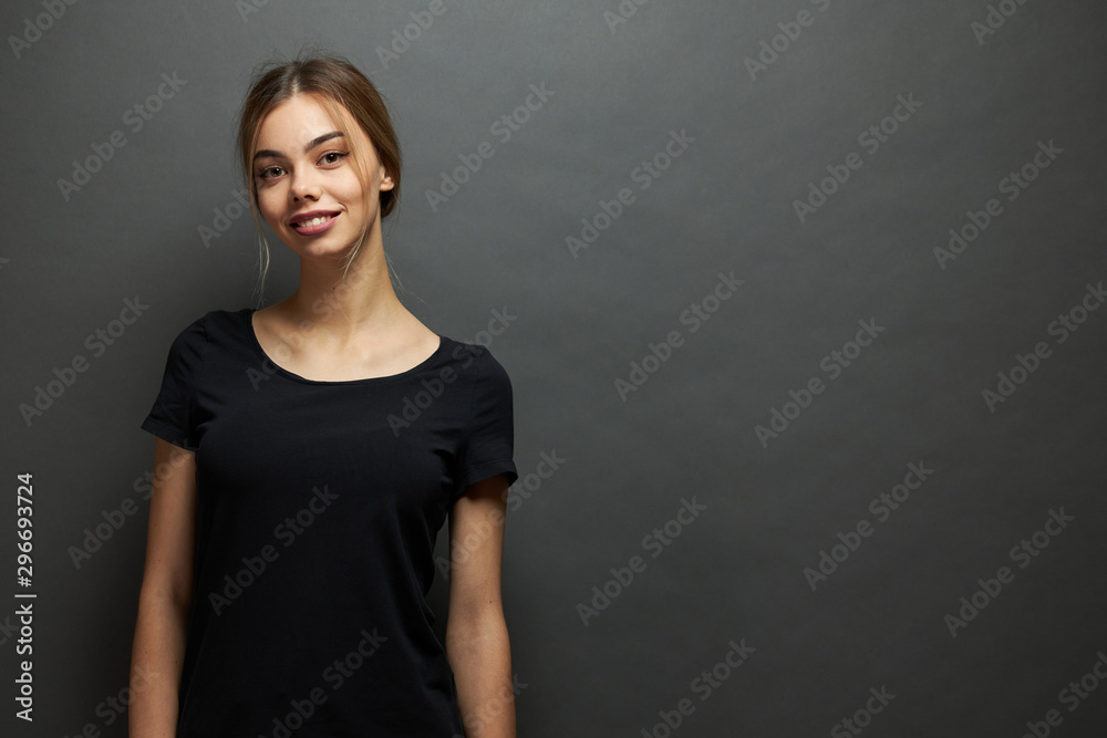 Sexy woman or girl wearing black blank t-shirt with space for your logo, mock up or design in casual urban style over gray background