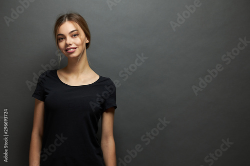 Sexy woman or girl wearing black blank t-shirt with space for your logo, mock up or design in casual urban style over gray background