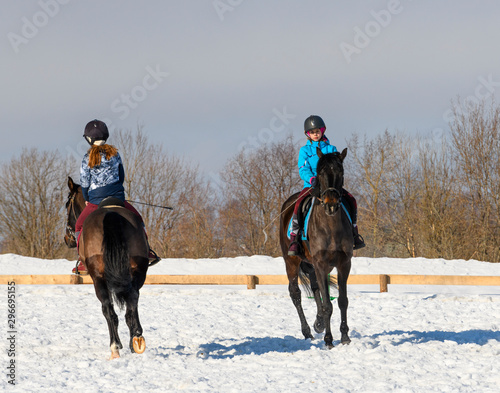 Two caucasian teenage girls, 13 years old, are horseback in winter.