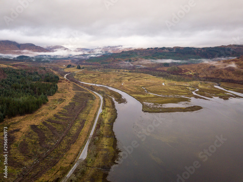 Road passing around Loch Eil and overlooking the brown wintery Scottish Highlands on an overcast grey day.