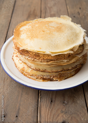 Honey or maple syrup pouring over crepes. Closeup view of stack of thin pancakes, blini