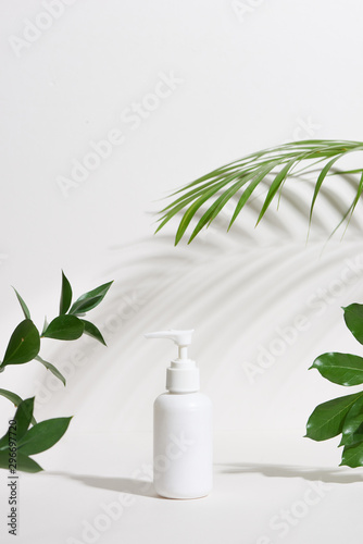 Blank white cosmetic bottle with a tropical leaf isolated on white background