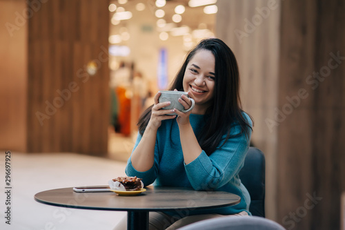 Cute plus size woman resting in cafe inside city mall