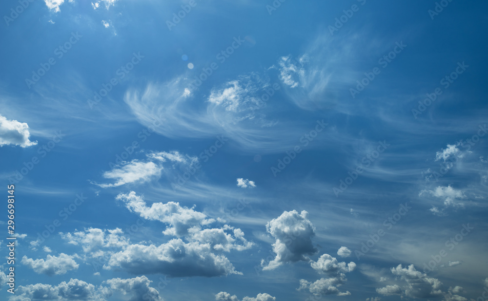 Some light cumuliform and cirrus clouds in the clean blue sky. - obrazy, fototapety, plakaty 