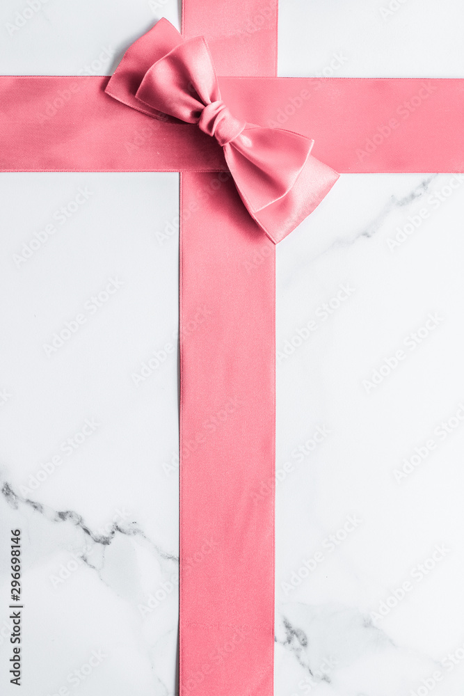 Pink silk ribbon and bow on marble background, girl baby shower