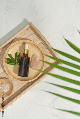 Serum bottle with massage salt on wood plate on white background. Flat lay spa and beauty concept. photo