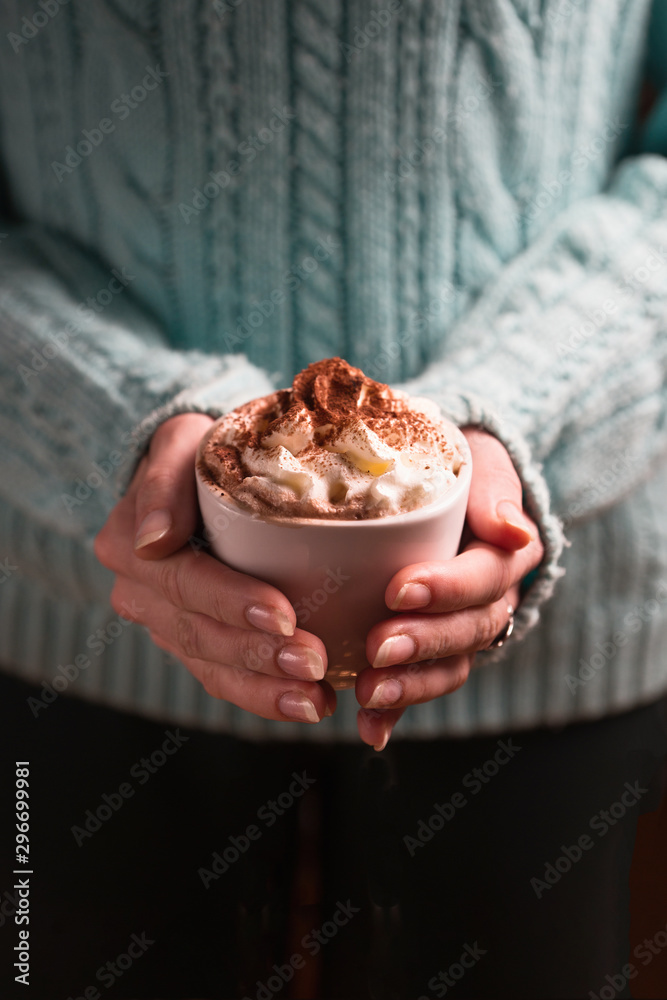 Woman holding mug of cocoa drink with whipped cream in hands Woman holding mug of cocoa drink with whipped cream in hands