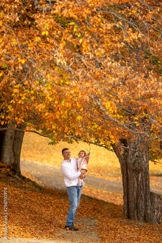 Happy family, dad, and little daughter are walking in the autumn forest .