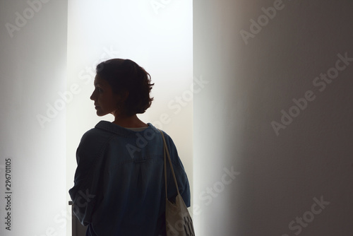 Young woman in a white hall photographed in profile with a strong backlight.