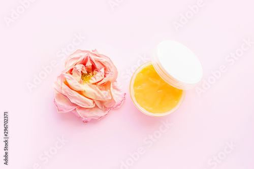 Open jar of cosmetic cream and rose on pink background. Concept of organic spa cosmetics. Flat lay, top view, copy space © Lyubov