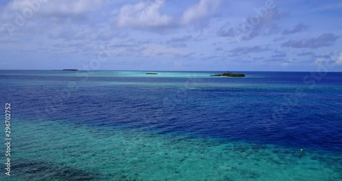 aerial descending tilt down shot of coral reefs, crystal clear water and corals with distant uninhabited island photo