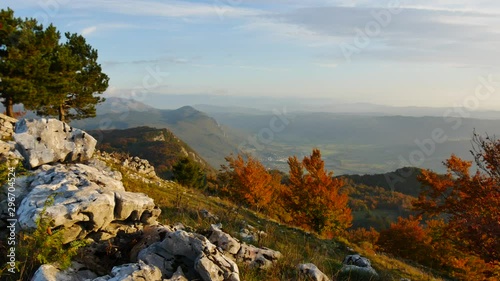 panoramic shot from a stonemade wall on a large valley with orange trees in the foreground in autumn photo