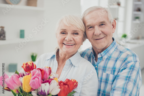 Close-up portrait of her she his he two nice attractive lovely cheerful cheery adorable people granny holding in hands big fresh natural blossom congrats spring in light white interior living-room