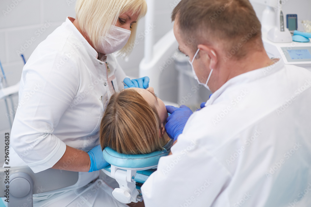 Obraz premium Doctor dentist treats teeth of a beautiful young girl patient. The girl on reception at the dentist. Doctor dentist treats tooth