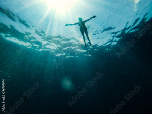 Woman floating in the sea and rays of light piercing through