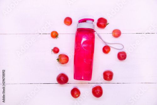 Pink tomato smoothie. Sports pink bottle on a white background top view. Sports nutrition and diet. Detox Raw Food Concept. Tomatoes around a pink plastic bottle