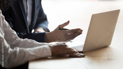 Close up of diverse businesspeople negotiate using laptop