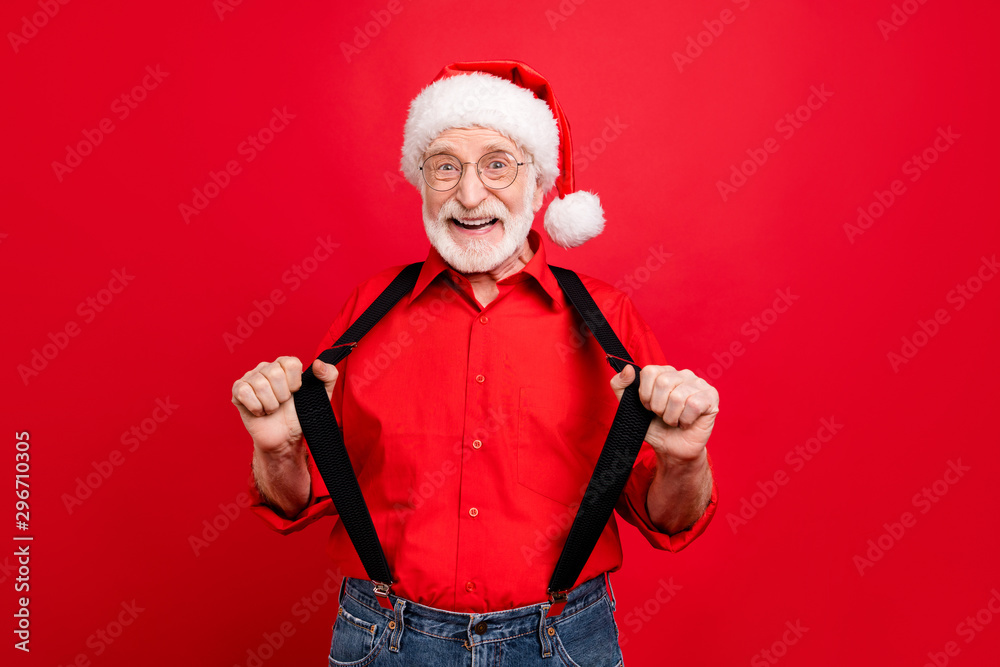 Portrait of his he nice trendy cheerful cheery glad excited bearded Santa Claus pulling suspenders isolated over bright vivid shine vibrant red background