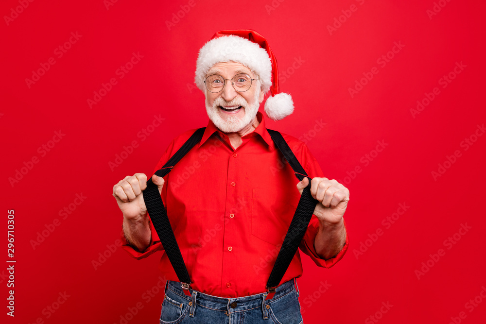 Portrait of his he nice trendy cheerful cheery glad excited bearded Santa Claus pulling suspenders isolated over bright vivid shine vibrant red background Portrait of his he nice trendy cheerful cheery glad excited bearded Santa Claus pulling suspenders isolated over bright vivid shine vibrant red background